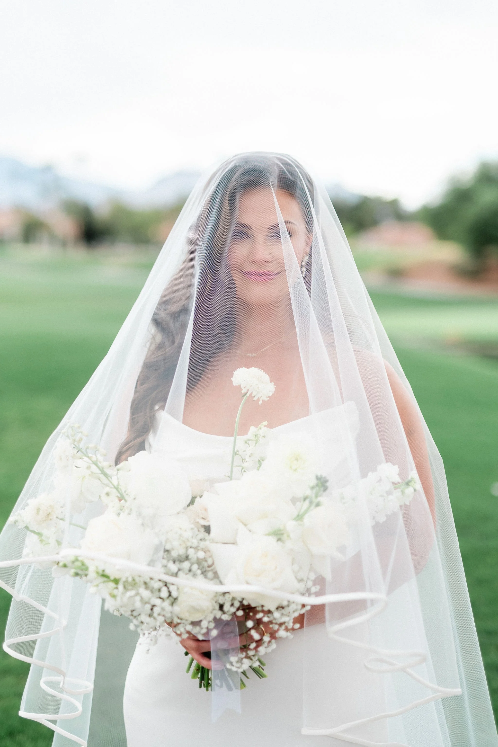 Bride looking through veil with white bouquet on golf course at Canyon Gate Country Club Las Vegas, hair and makeup by Marai A for Amelia C & Co, photography by Kristen Marie Weddings