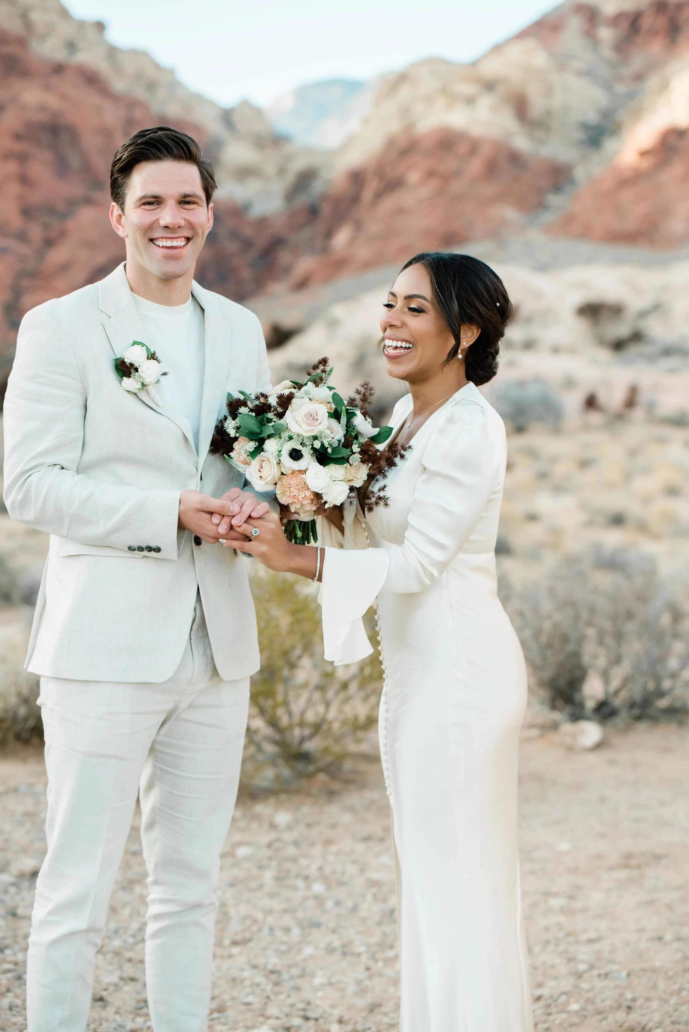  Martinique and James walking hand in hand through Red Rock Canyon elopement desert landscape, hair and makeup by Luci for Amelia C & Co, photography by Cactus Collective Weddings