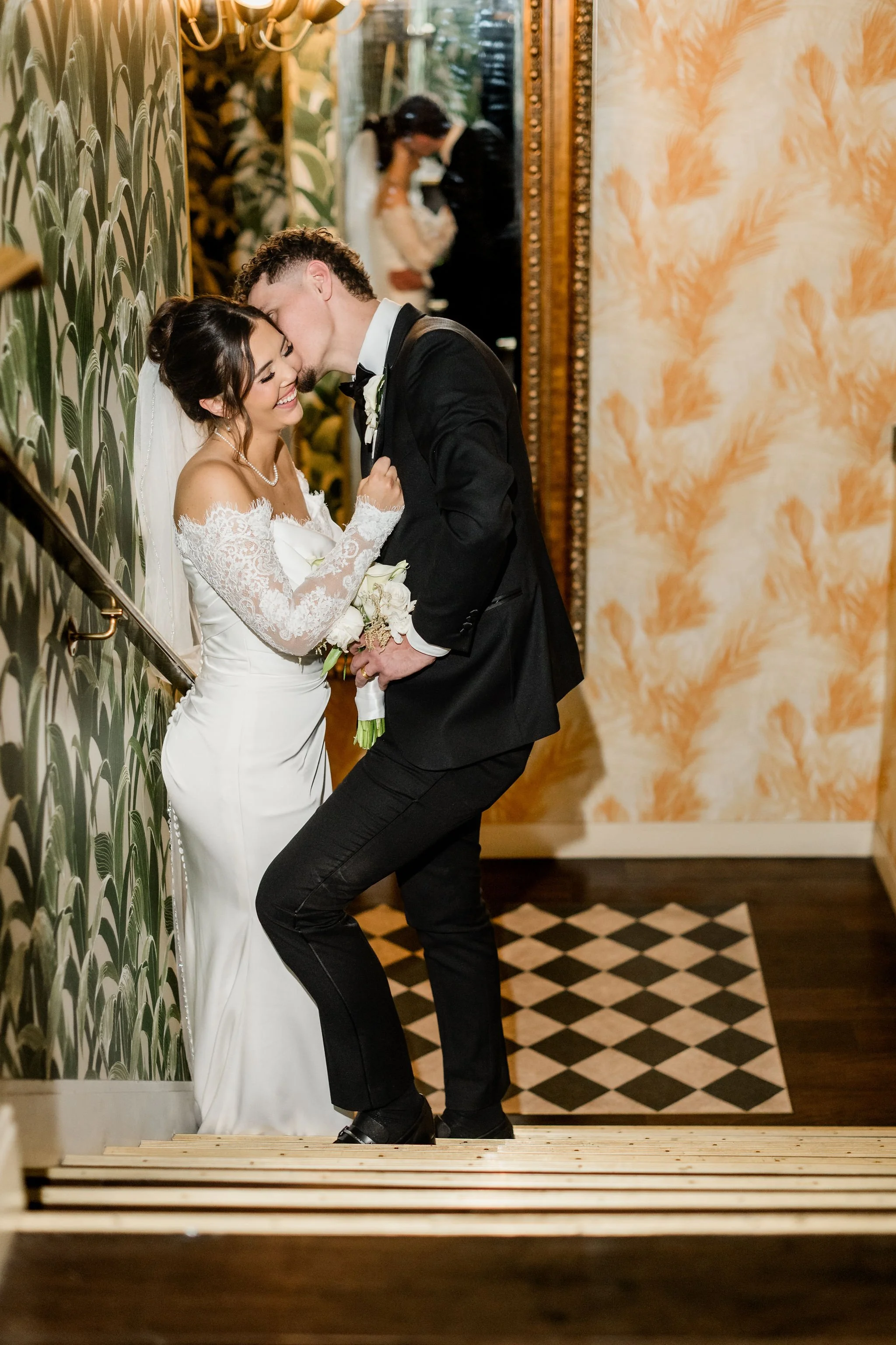 Groom Lukas kissing bride Jessica's cheek on staircase at Hard Rock Hotel Las Vegas wedding, hair by Katie and makeup by Aimee for Amelia C & Co, photography by Liz Le