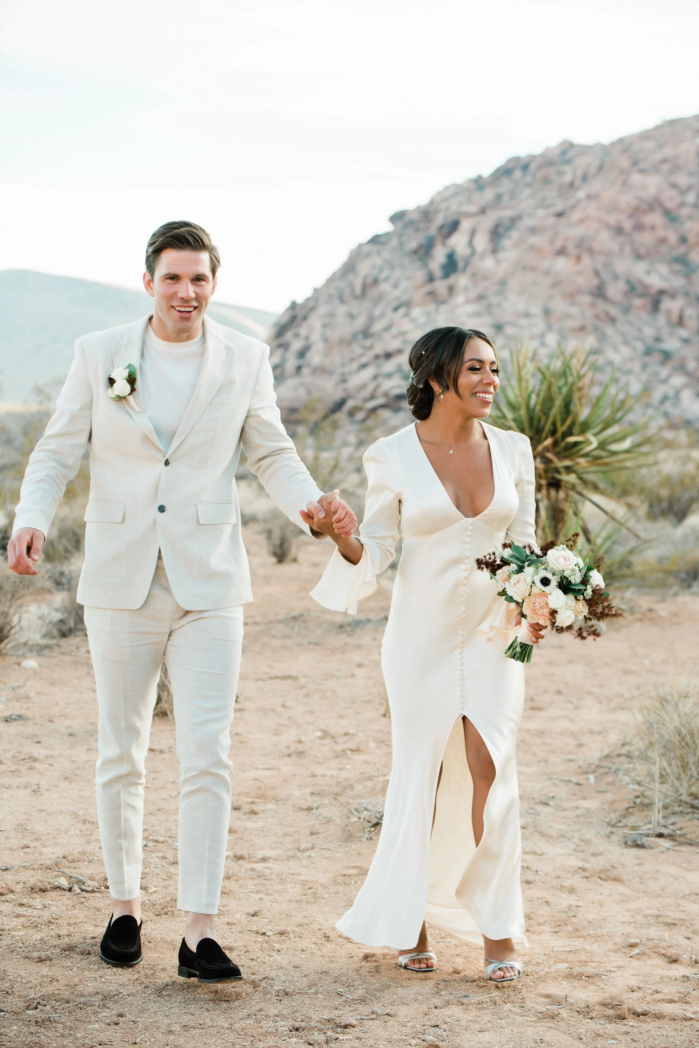 Martinique and James laughing together holding bouquet during Red Rock Canyon elopement, hair and makeup by Luci for Amelia C & Co, photography by Cactus Collective Weddings