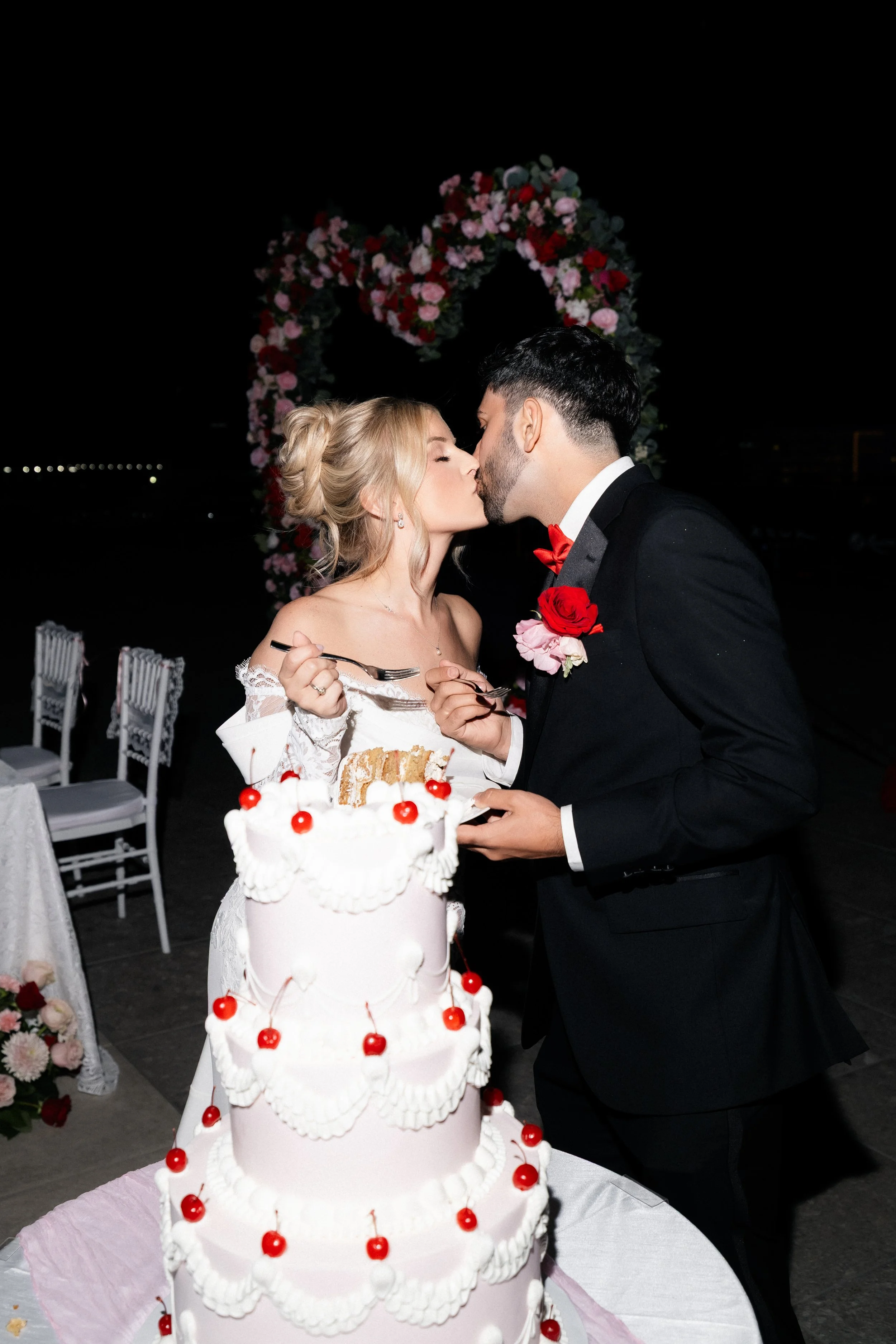 Bride and groom kissing during cake cutting at nighttime Las Vegas wedding, bridal hair by Katie A and makeup by Aimee A for Amelia C & Co, photography by Risky Exposure