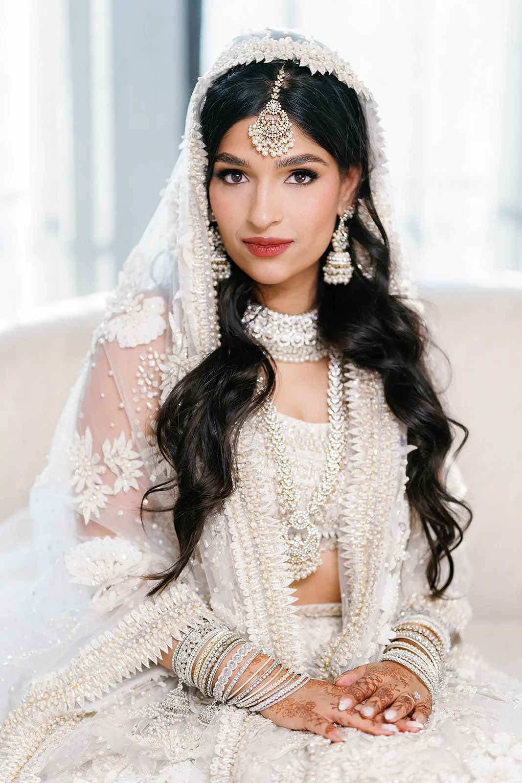 Close-up bridal portrait of Trusha with dupatta, maang tikka, and pearl jewelry at JW Marriott Las Vegas wedding, hair by Courtney and makeup by Natalia for Amelia C & Co, photography by Chernogorov Photography