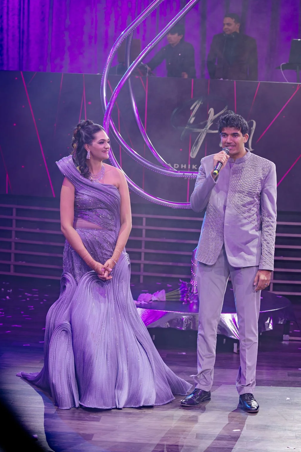 Indian bride and groom on stage at Las Vegas engagement celebration, bride in lavender embellished gown, hair by Karen K and makeup by Natalia W for Amelia C & Co, photography by Elizabeth Burgi