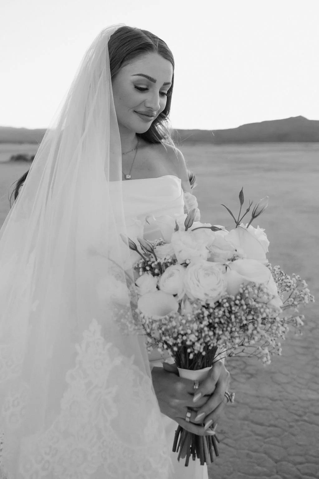 Black and white bridal portrait of Cameron with veil and white rose bouquet at Dry Lake Bed Las Vegas elopement, hair and makeup by Marai for Amelia C & Co, photography by Sofia Teresa