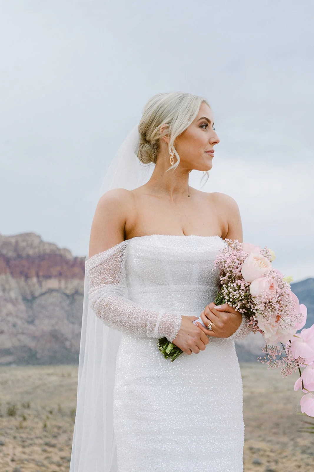 Bridal portrait at Red Rock Canyon Las Vegas elopement, bride in sequin mini dress with pink bouquet and bridal updo, hair and makeup by Luci L for Amelia C & Co, photography by Kristen Joy