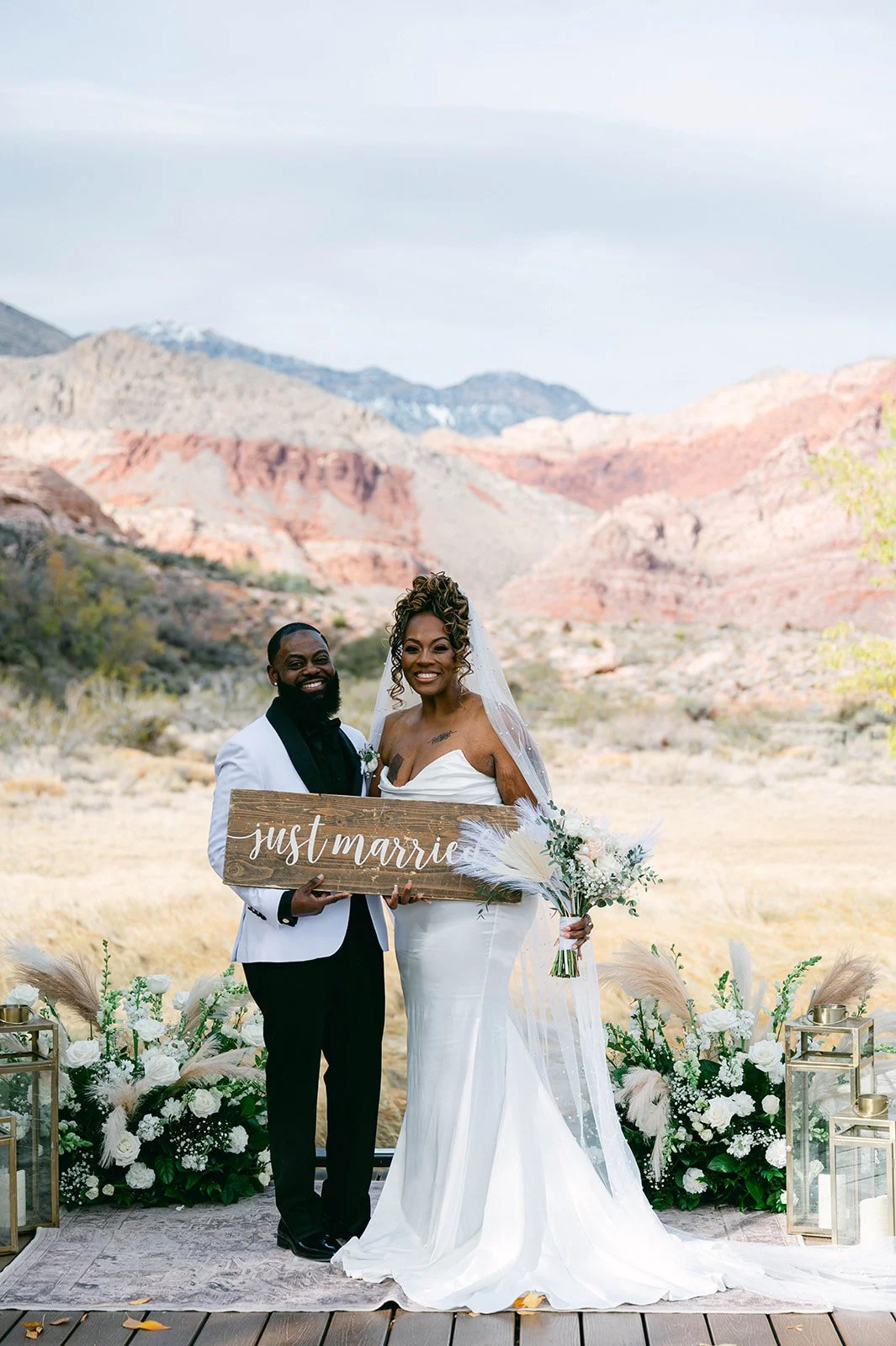 Aretha and Jaxon holding just married sign on ceremony deck at Red Spring Boardwalk Las Vegas elopement with red rock canyon backdrop, hair by Courtney and makeup by Natalia for Amelia C & Co, photography by Desert Wildflower