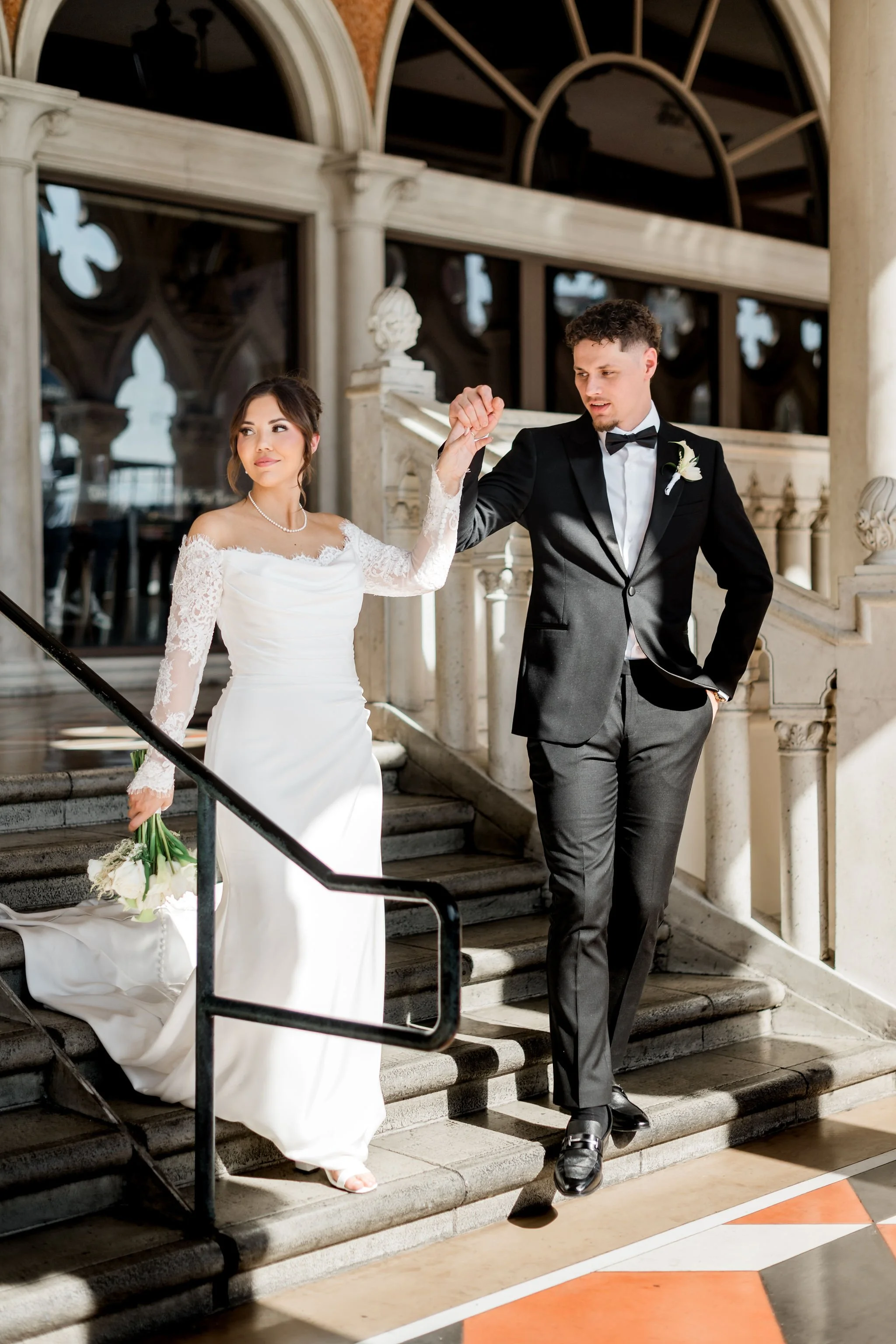 Bride Jessica and groom Lukas walking down marble staircase at The Venetian Las Vegas, hair by Katie and makeup by Aimee for Amelia C & Co, photography by Liz Le