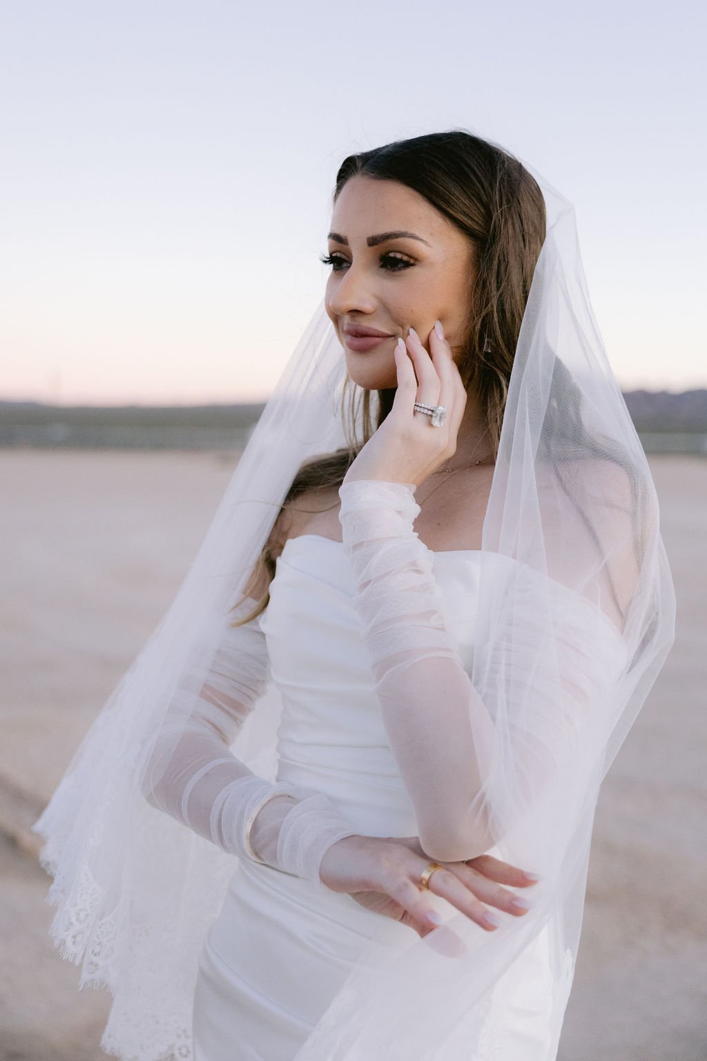 Cameron in veil and sheer sleeve gloves holding white bouquet at Dry Lake Bed Las Vegas elopement, hair and makeup by Marai for Amelia C & Co, photography by Sofia Teresa