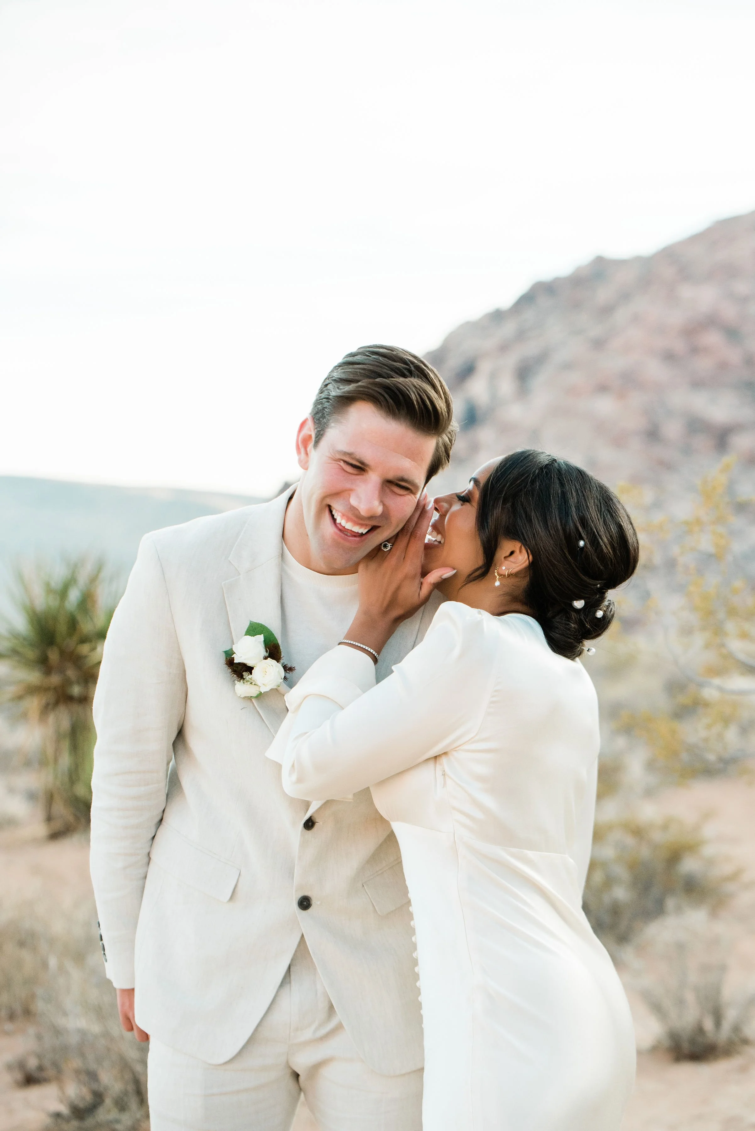 Martinique whispering in James's ear laughing during Red Rock Canyon elopement, hair and makeup by Luci for Amelia C & Co, photography by Cactus Collective Weddings