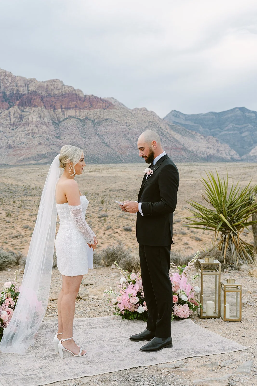 Groom reading vows to bride at Red Rock Canyon Las Vegas elopement, bridal updo and soft glam makeup by Luci L for Amelia C & Co, photography by Kristen Joy