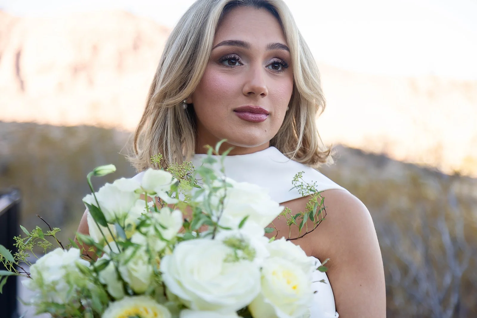 Bridal beauty close-up of Melysa with blonde blowout and mauve lip at Red Spring Boardwalk Las Vegas elopement, hair by Luci and makeup by Natalia for Amelia C & Co, photography by Onyx & Arrow