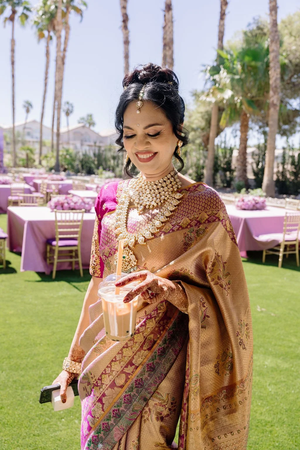 Guest in gold and magenta silk saree with traditional jewelry at Indian engagement celebration in Las Vegas, hair and makeup by Amelia C & Co, photography by Elizabeth Burgi