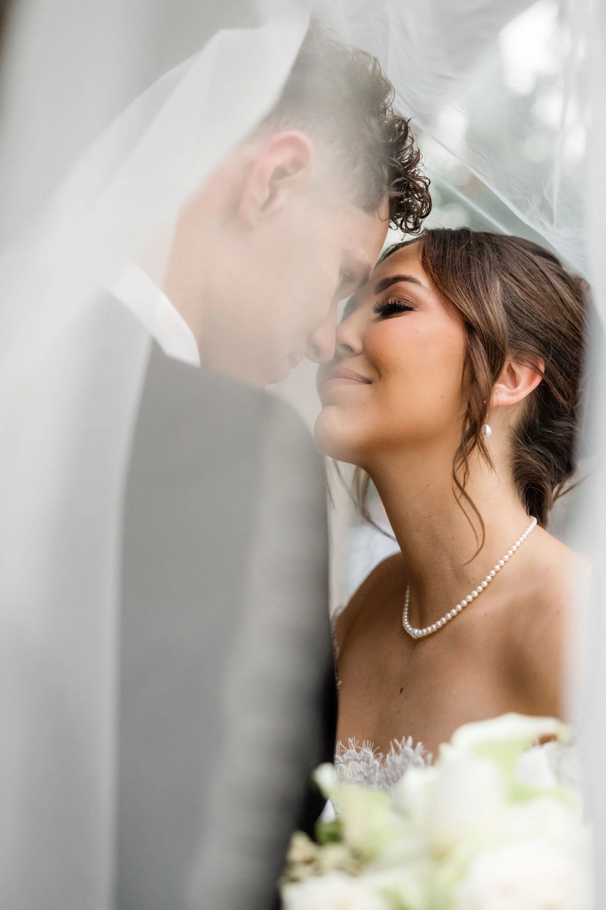  Intimate close-up of bride Jessica and groom Lukas with foreheads touching under veil at Hard Rock Hotel Las Vegas wedding, hair by Katie and makeup by Aimee for Amelia C & Co, photography by Liz Le