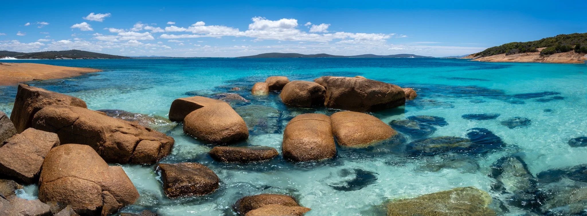 Clear Denmark WA ocean in the background with large rocks in the foreground.