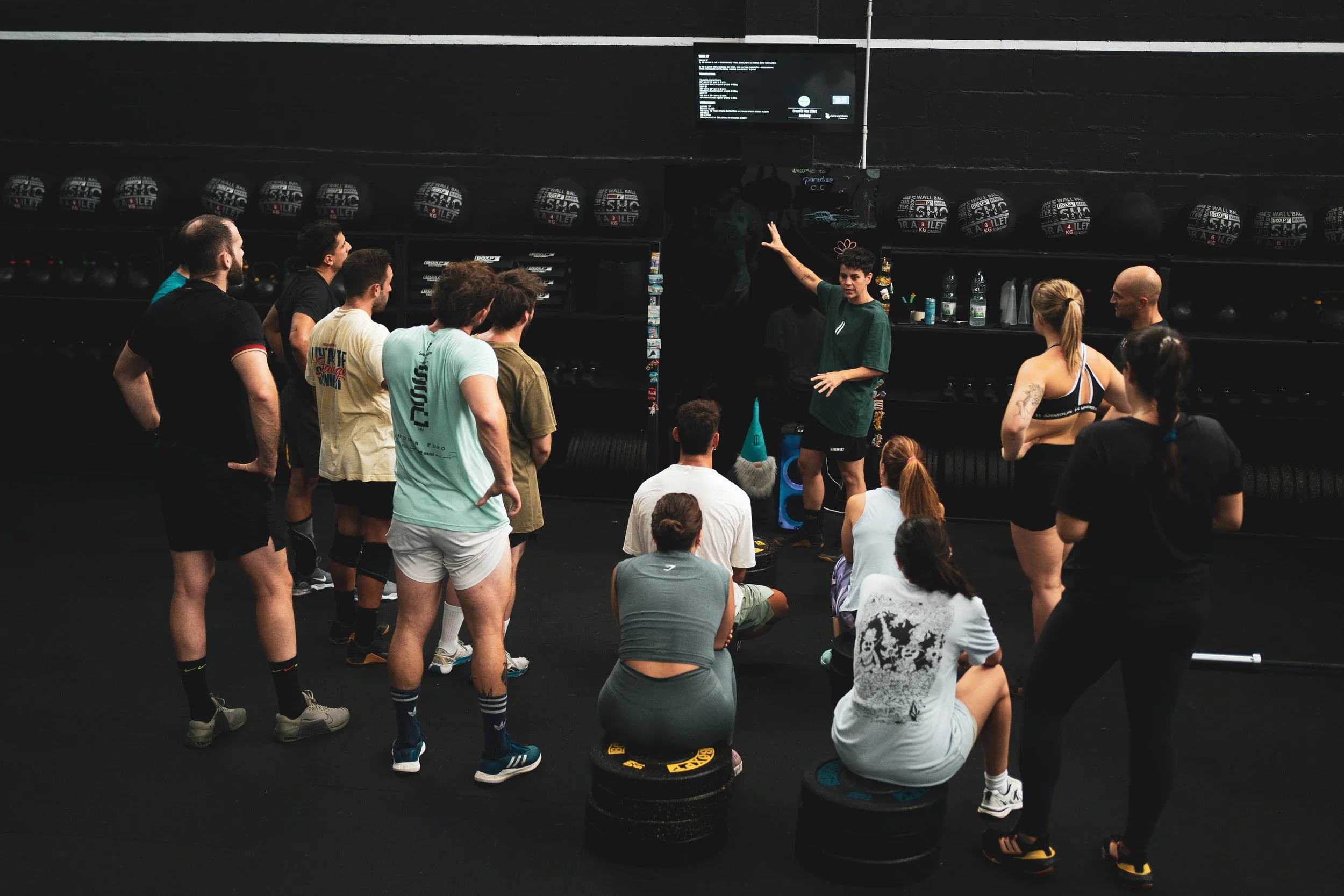 Grupo de alumnos escuchando a la entrenadora antes de una clase de CrossFit en Max Effort Academy, Cambre
