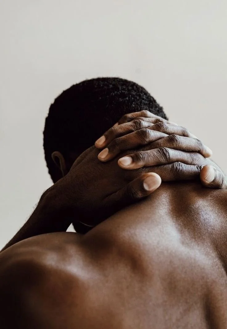 Un homme à la peau foncée, vu de dos, qui tient sa tête avec ses mains.