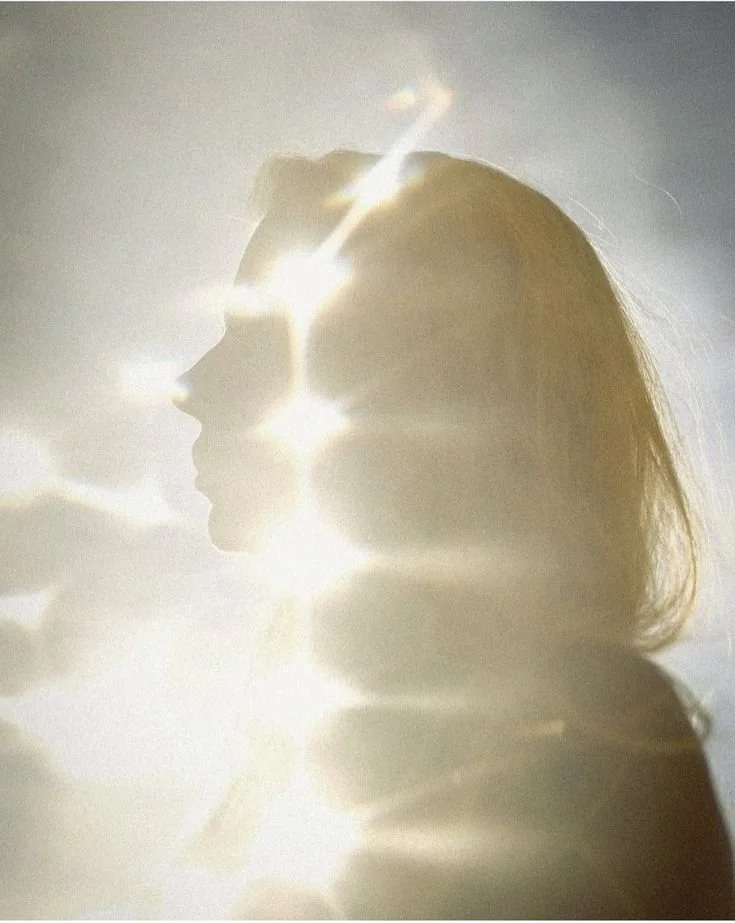 Silhouette d'une femme ou d'une personne avec la lumière du soleil brillant à travers d'elle, créant un effet lumineux et éclatant.