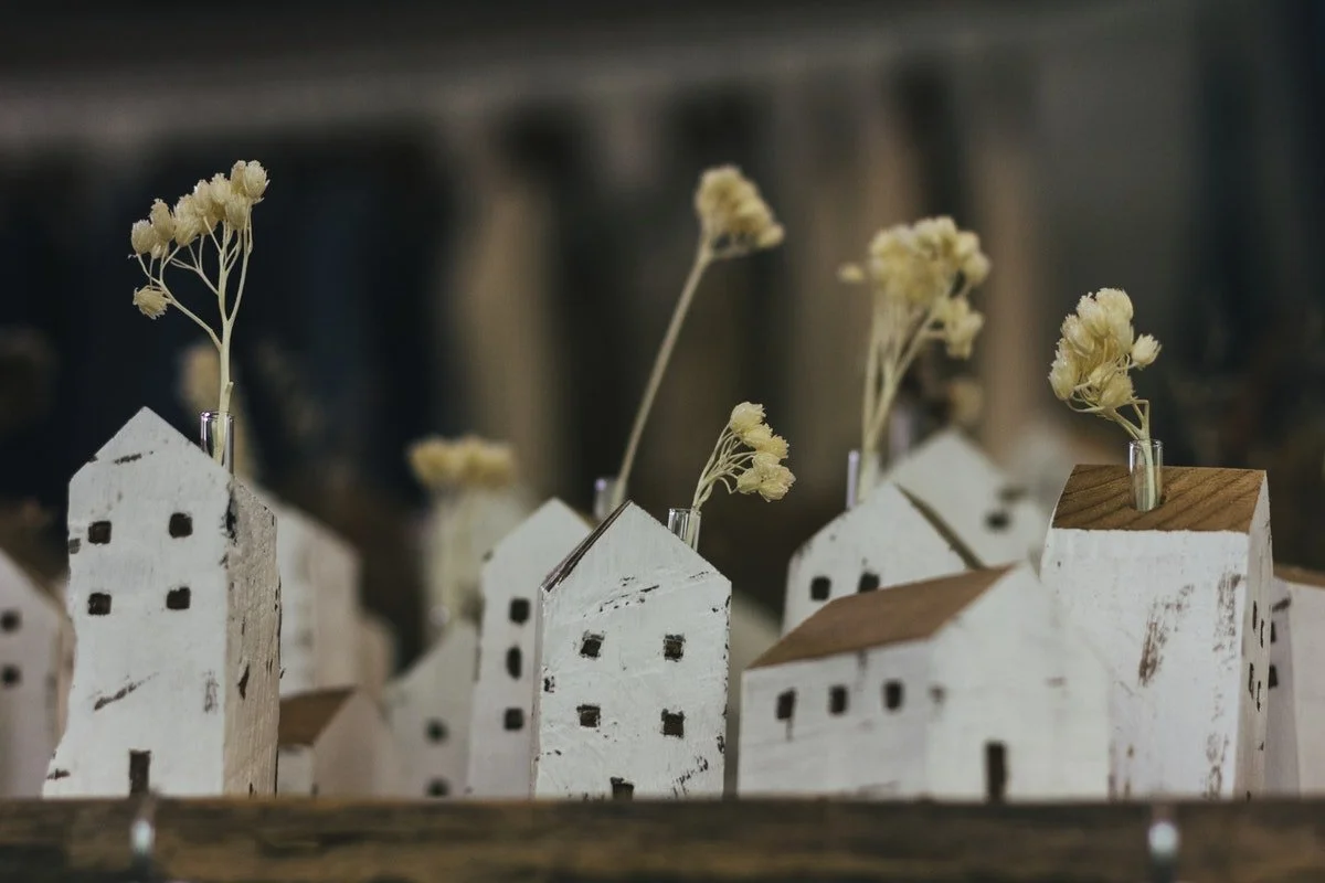 Petites maisons en bois blanc avec des toits en bois, décorées avec des brins de fleurs séchées dans de petites bouteilles. Cours à domicile, studio.