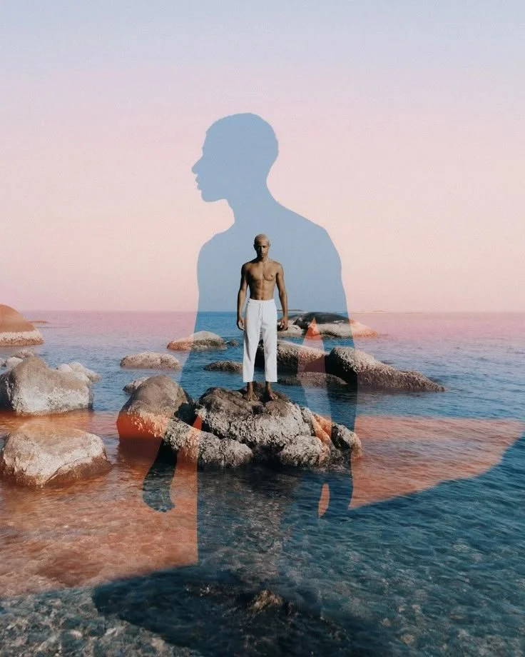 Un homme debout sur une roche au bord de la mer avec un effet de double exposition montrant une silhouette géante en arrière-plan