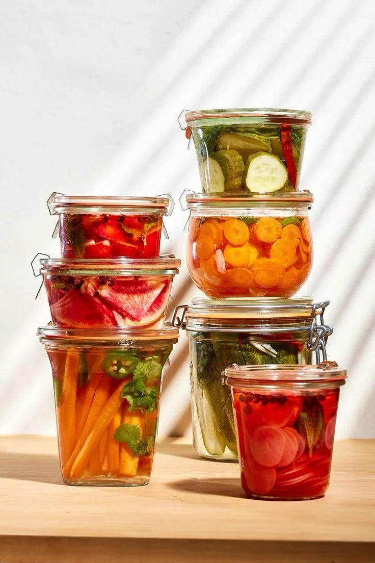 Pot de légumes marinés avec carottes, concombres, tomates, courgettes, radis, jalapeños, et autres légumes dans des bocaux en verre