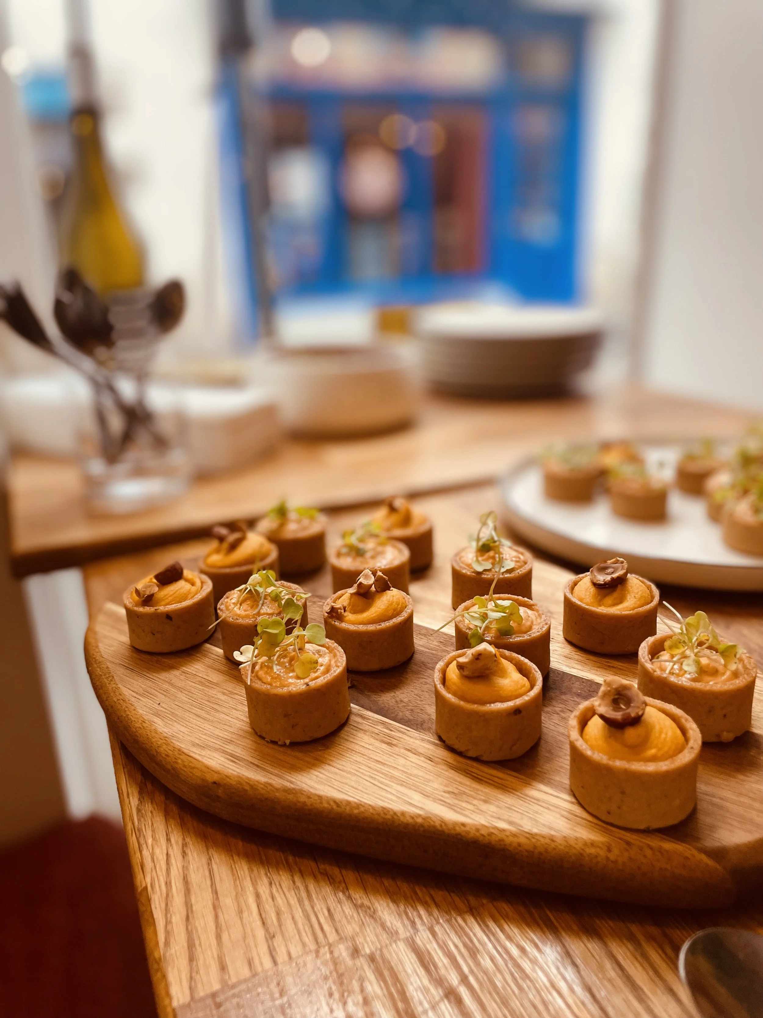 Petits amuse-gueules servis sur une planche en bois, garnis de garnitures diverses.