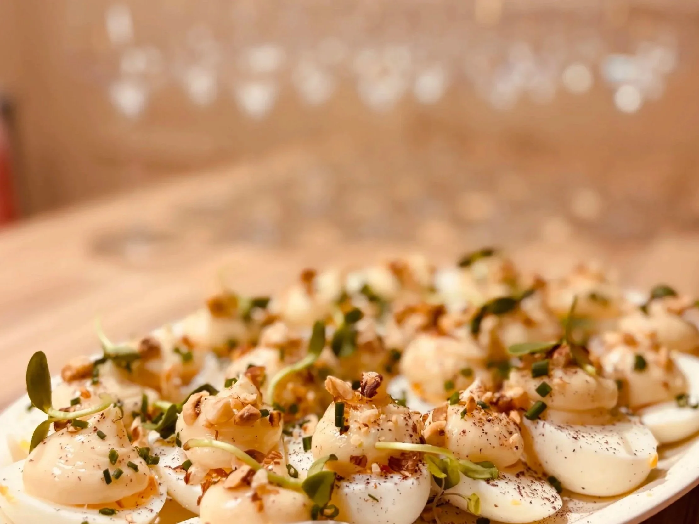 Une assiette d'œufs mollets garnis de graines, herbes finement coupées, et paprika, avec de la mayonnaise ou une sauce blanche en fond.