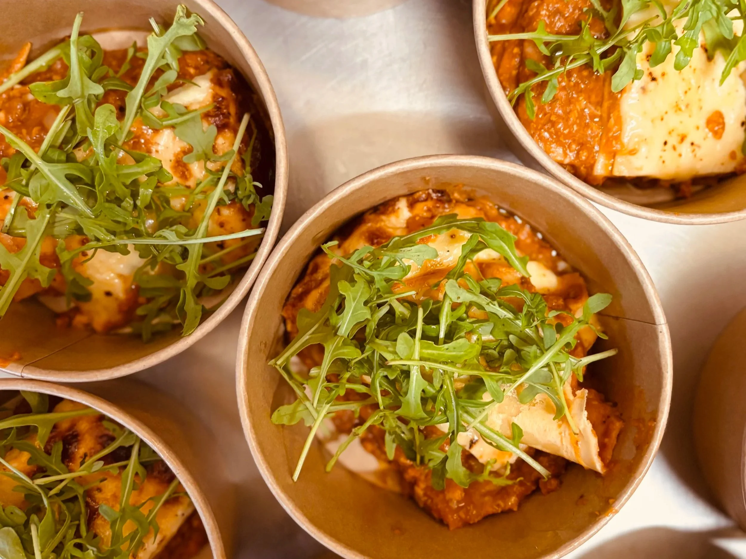 Mini casseroles en bois remplies de chili con carne garnishé de microgreens.
