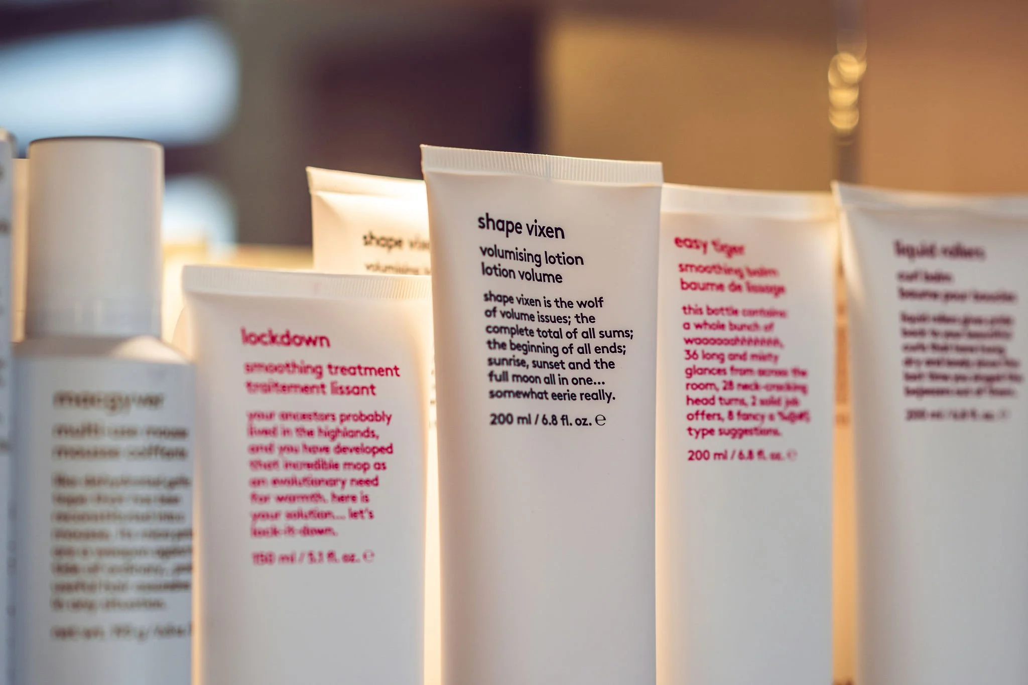 Close-up of Evo products which come in white cosmetic tubes with black and pink text on them, including product names and descriptions.