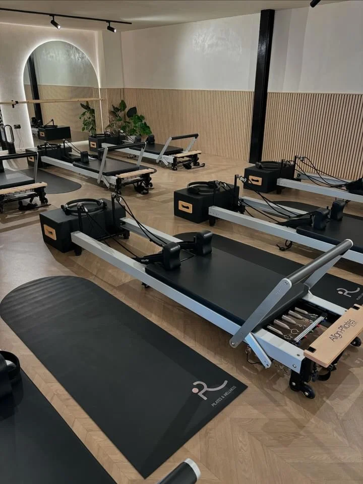 Pilates or yoga studio with Reformers, mats, and a plant.