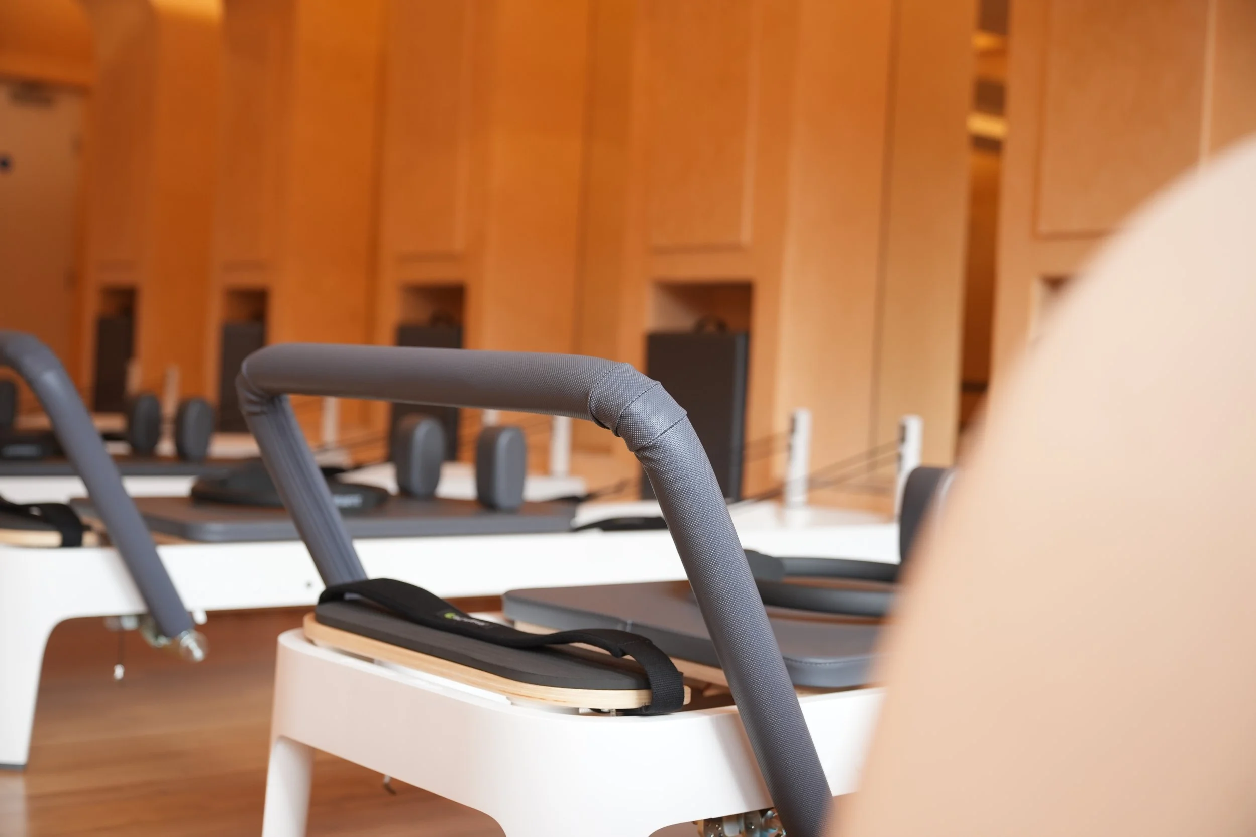 Row of exercise or therapy equipment with foam paddles and black straps, in front of wooden wall panels in a gym or therapy center.