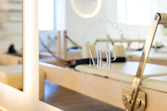 Pilates reformer machine in a bright, modern gym with large windows and natural lighting.
