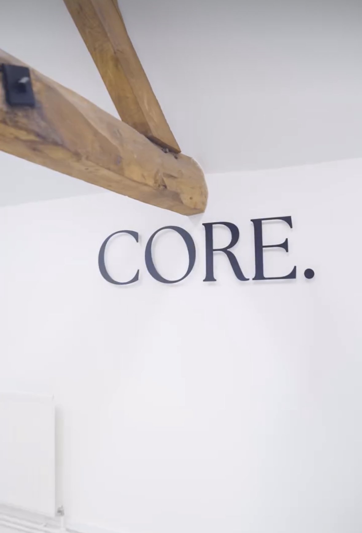 Close-up of a wooden ladder with the word 'CORE.' printed on a wall underneath.