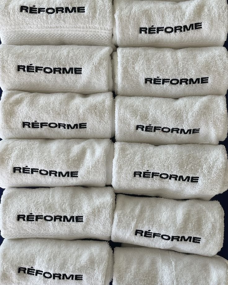 Ten white towels with the word "Réforme" embroidered in black on each one, arranged in two columns and five rows.