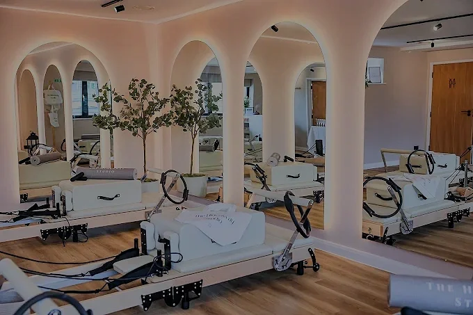 Fitness studio with Pilates reformer machines, mirrors, and indoor plants.