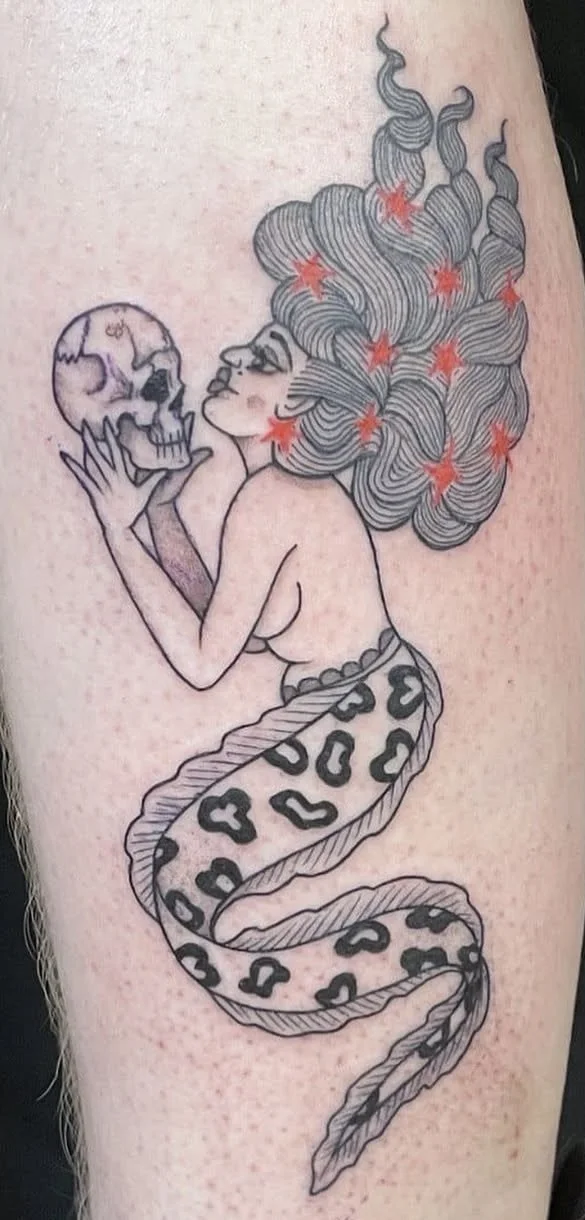 Fineline tattoo of a folklore mermaid with flowing hair holding a skull, medieval memento mori style