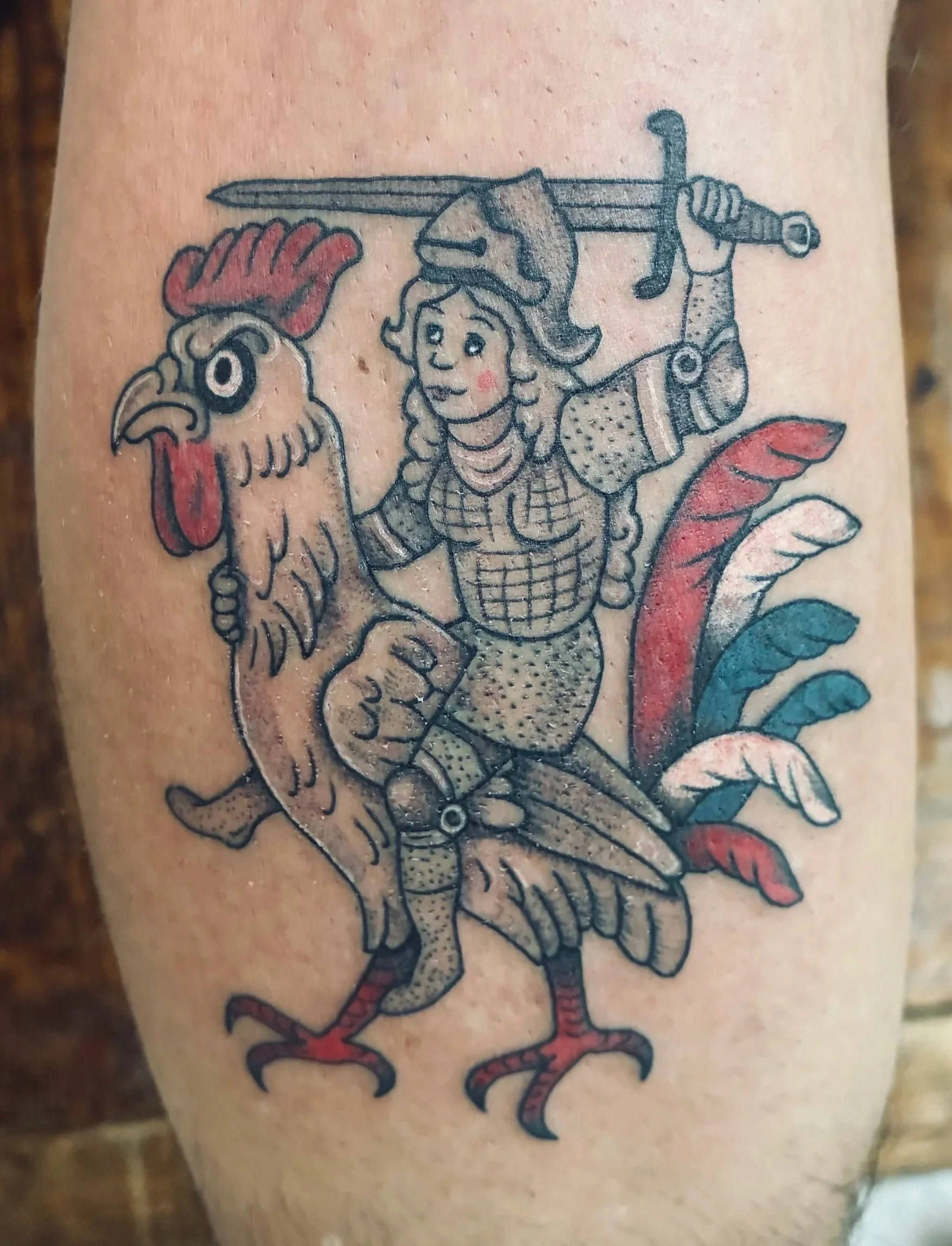 Color tattoo of a female knight in armor riding a rooster, with a sword and colorful feather plumes, medieval illuminated manuscript style