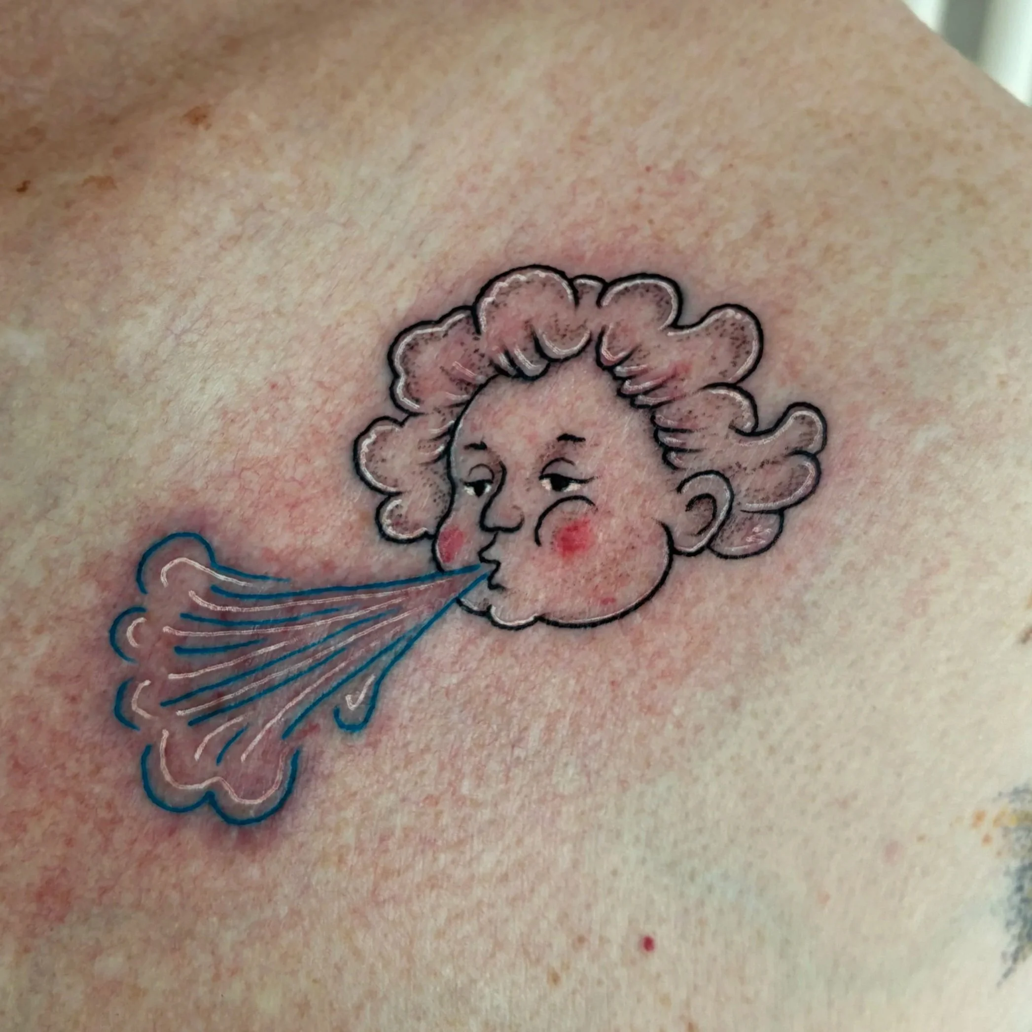 Color tattoo of a cherub face blowing wind, illustrative whimsical design