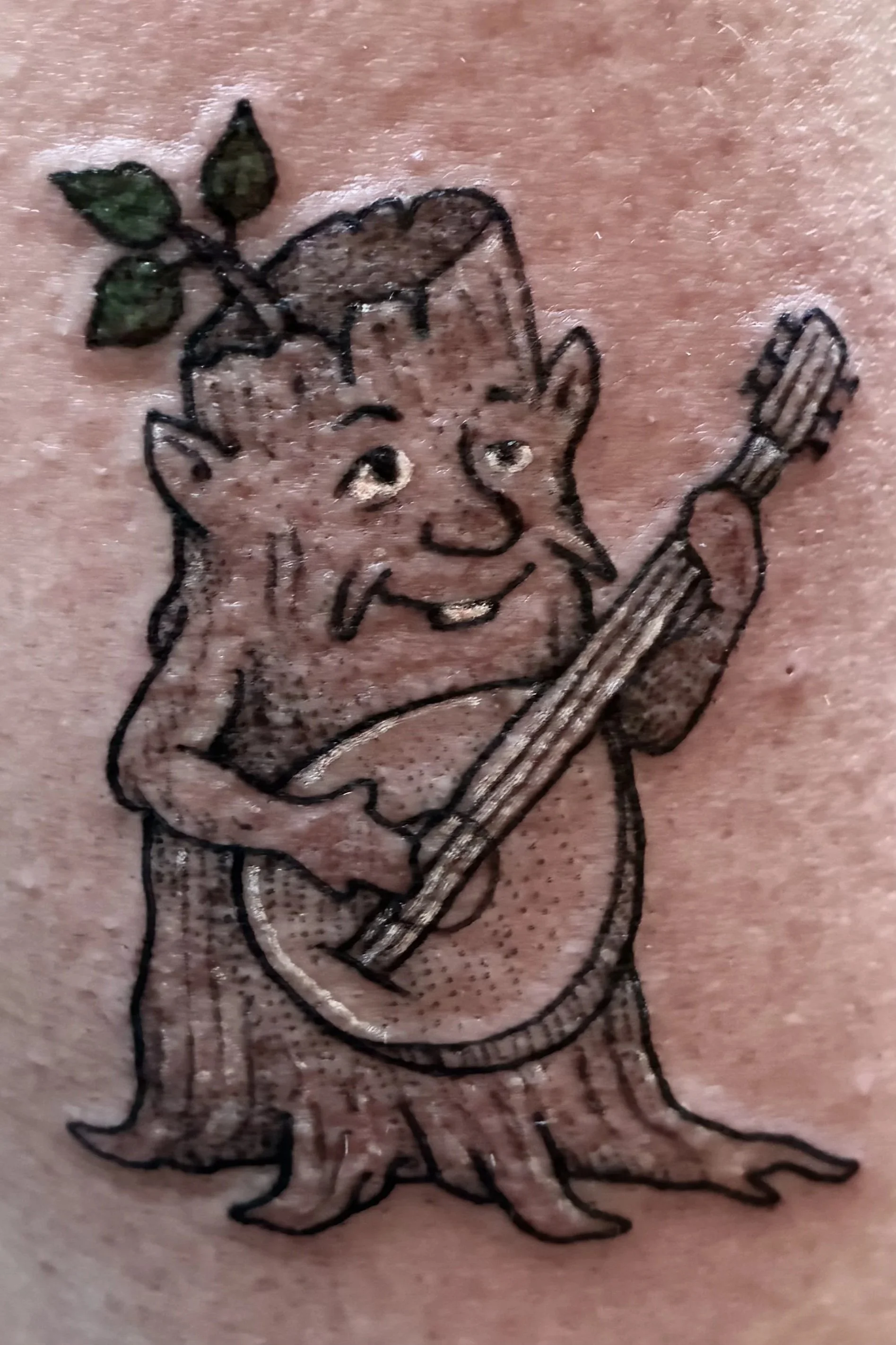 Color tattoo of a folklore smiling tree creature playing a guitar, whimsical fantasy character design
