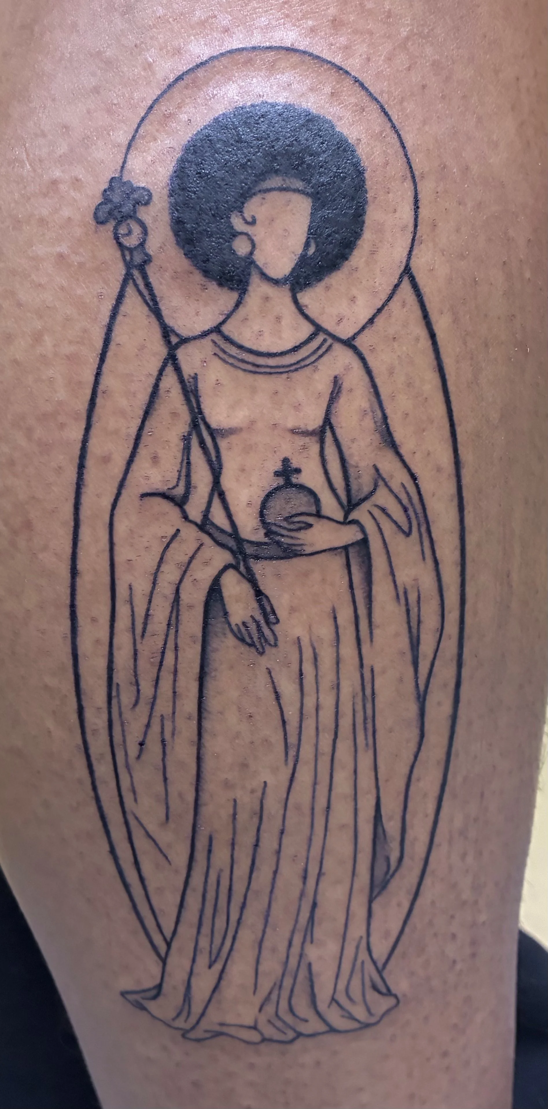 Fineline tattoo of a robed saint with an afro and halo holding insignia and staff, religious illustration style
