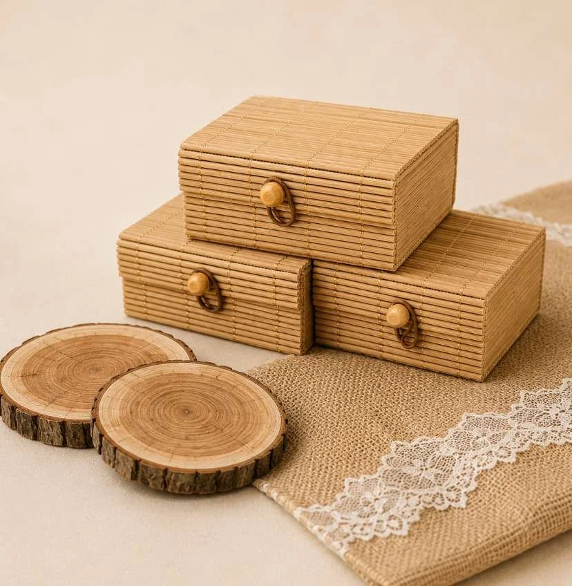 Three bamboo storage boxes with small wooden knobs, placed on a beige cloth with lace trim, and two wooden coasters nearby.