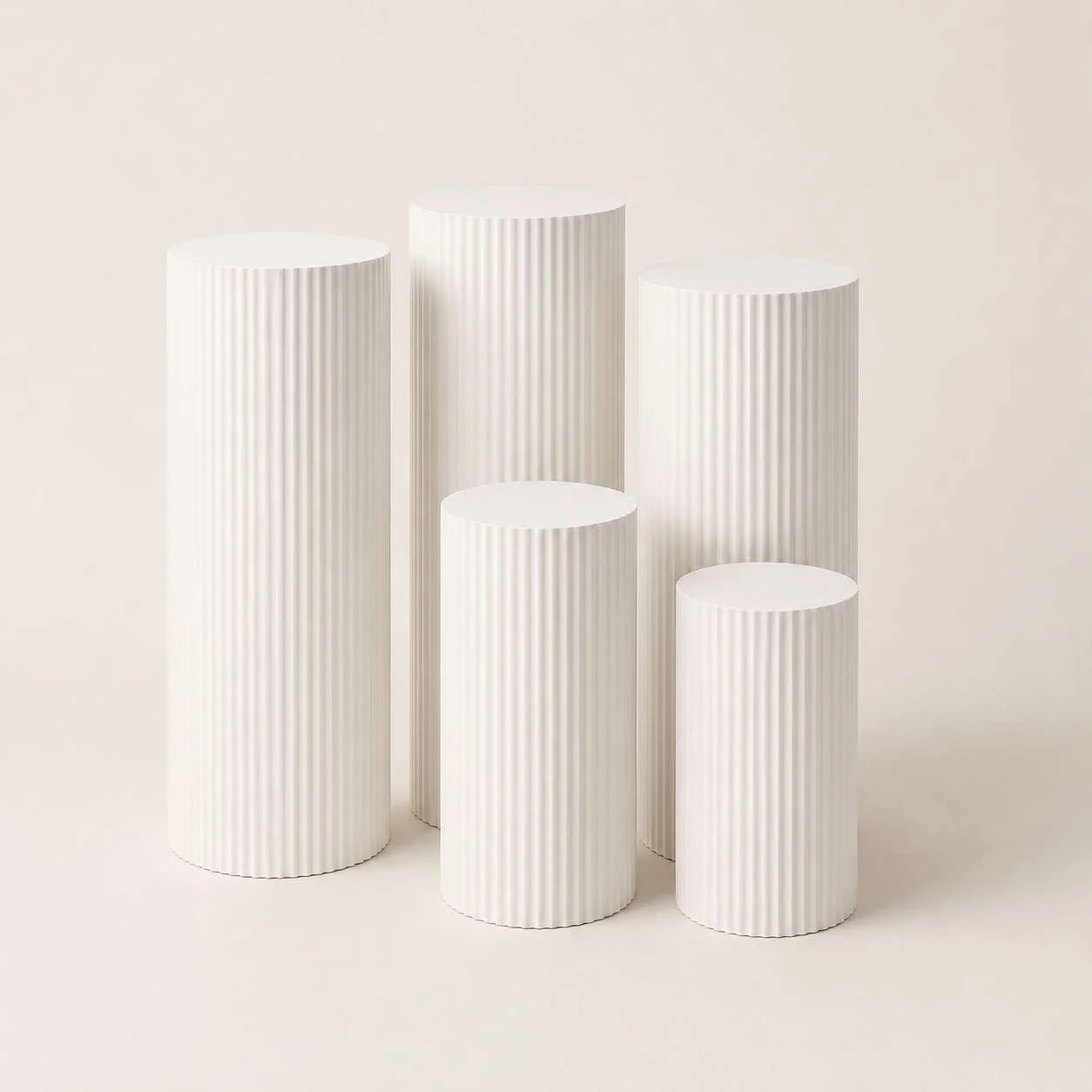 Five white ribbed cylindrical pedestals of varying heights arranged against a neutral background.