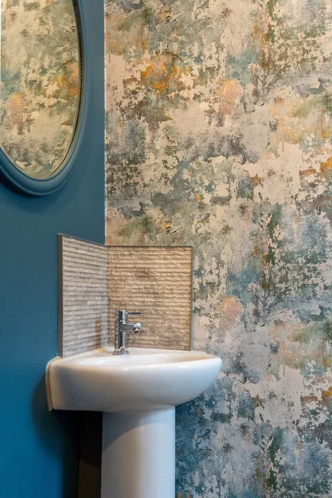 Modern white pedestal bathroom sink against teal and textured botanical-pattern wall