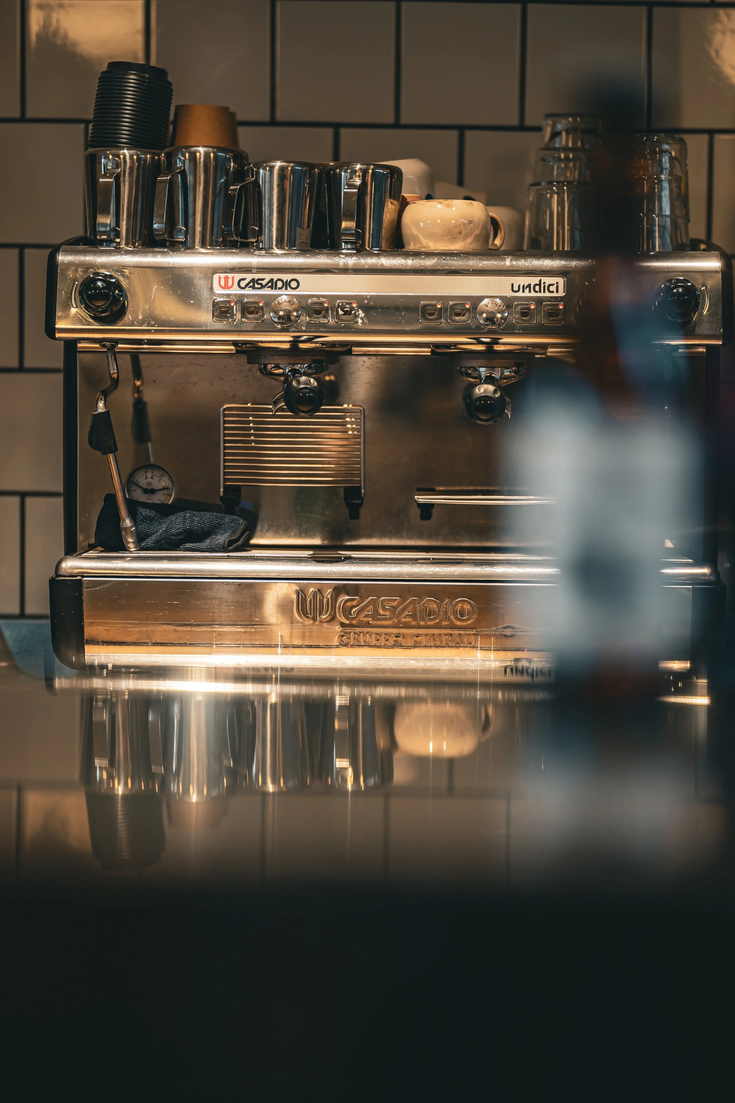 En professionell espressomaskin på ett café eller restaurang, med koppar och glas på toppen.