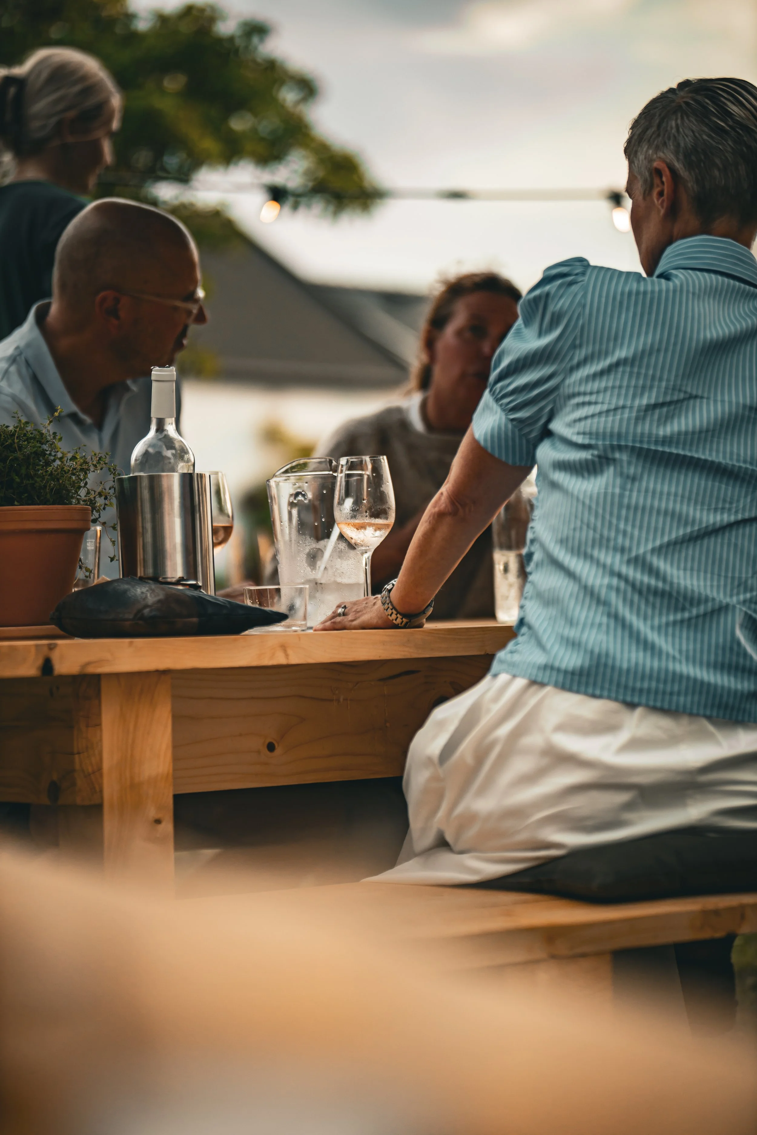 Grupp av människor som njuter av en middag utomhus, samtal och drycker