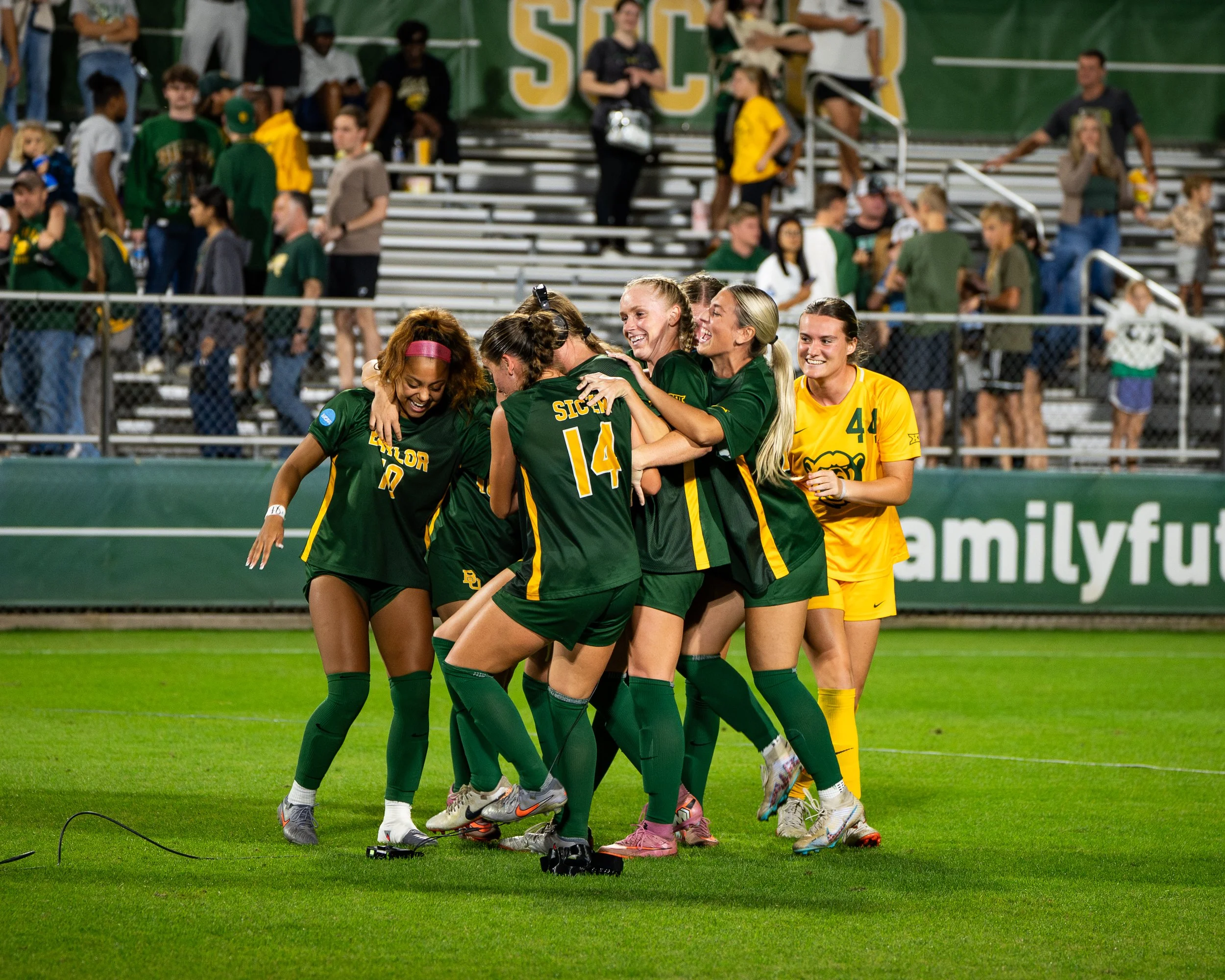 Group of female soccer players celebrating on the field during a game.