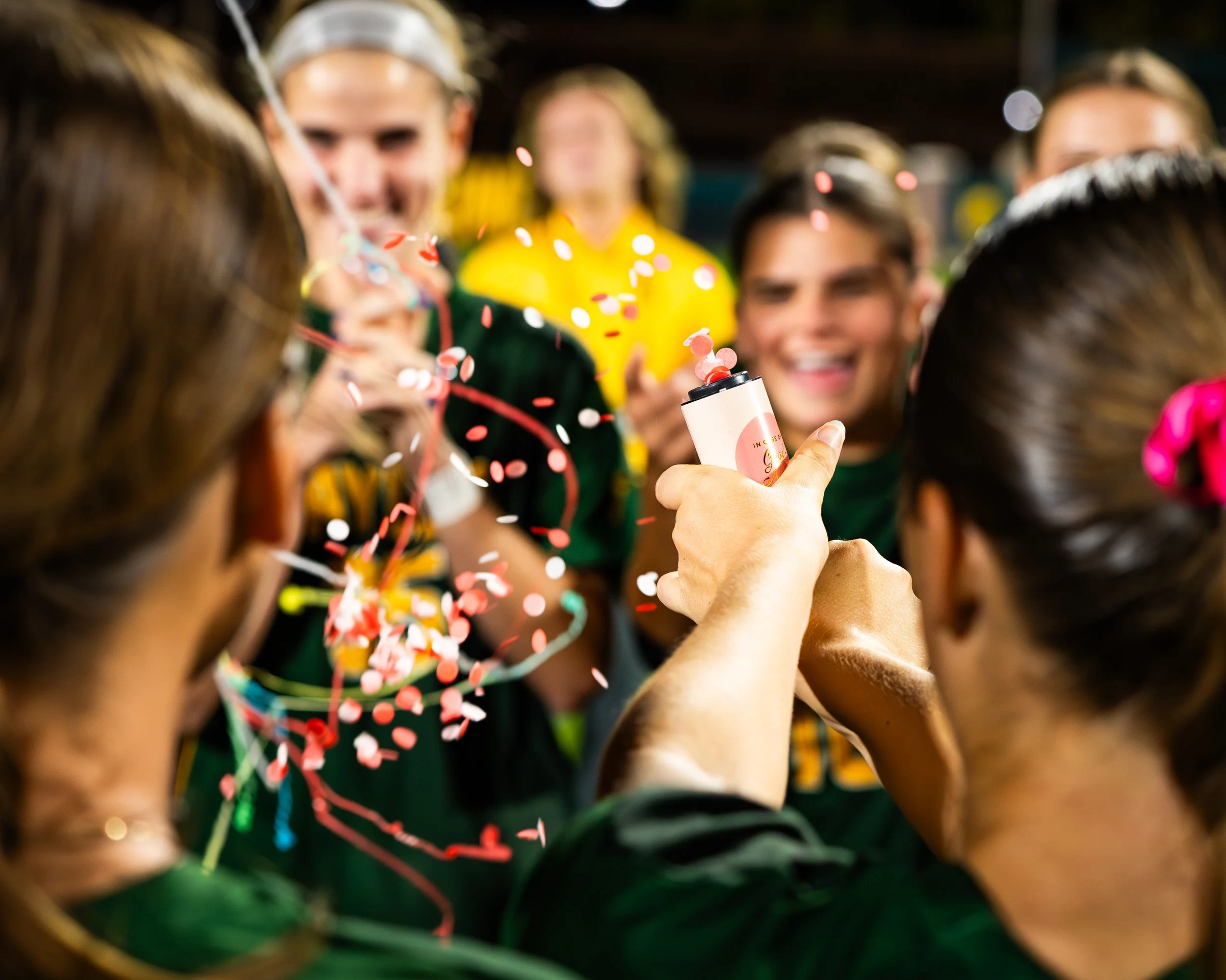 People celebrating with confetti and a confetti popper in a festive environment.
