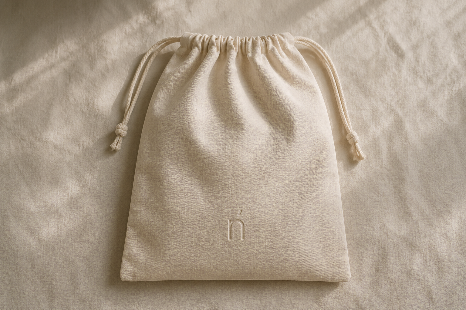 Nenúfar cotton garment bag with blind embossed logo for luxury coat storage.