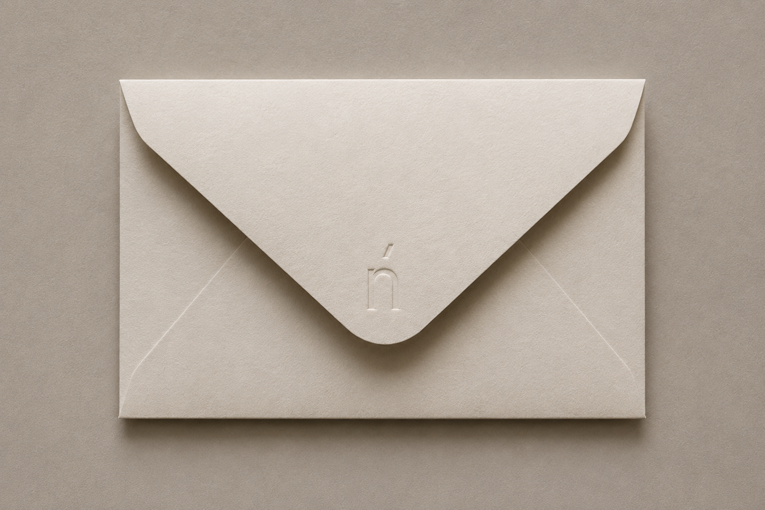 A beige Nenúfar envelope with a flap seal embossed with the Nenúfar Logo Monogram on the flap, resting on a beige background.