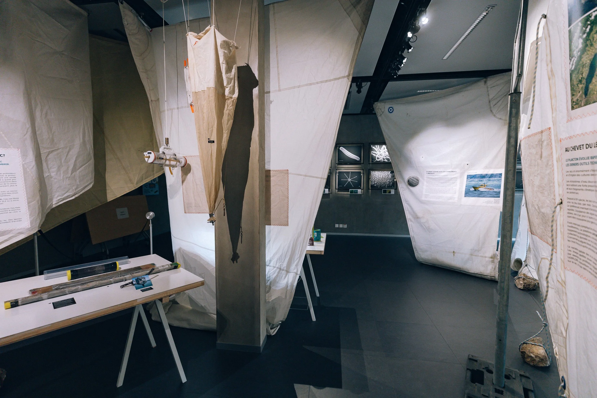Scénographie d'exposition immersive en voiles de bateaux dans un musée avec affiches, objets et panneaux d'information sur le thème du plancton.