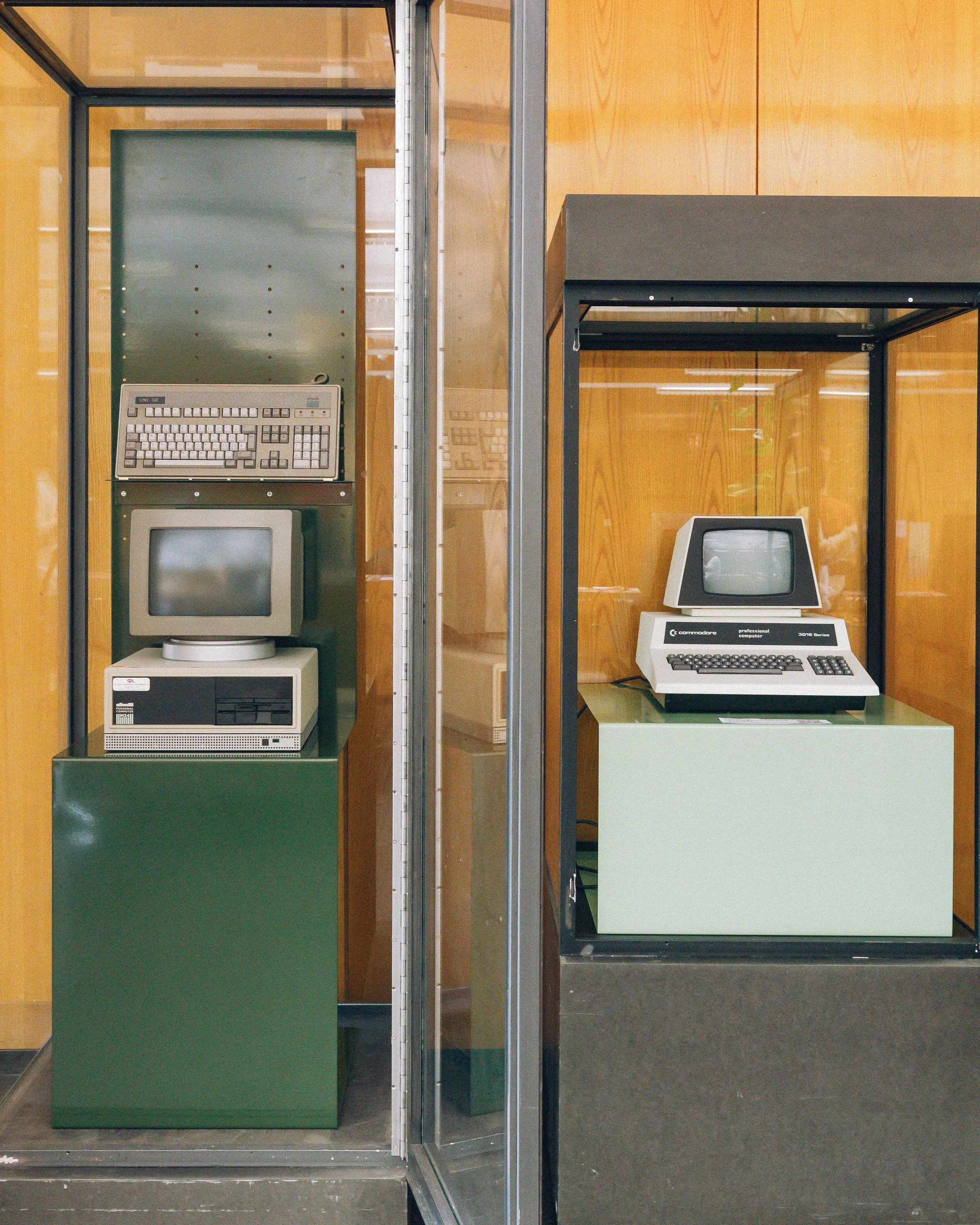 Vitrine contenant un ordinateur vintage, une vieille imprimante et un écran, dans un musée ou une collection de matériel informatique rétro.
